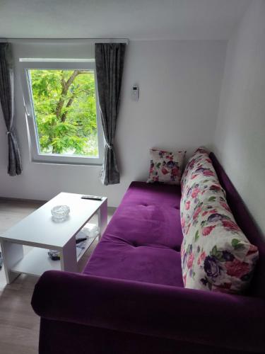 a purple couch in a living room with a table at City River View in Foča