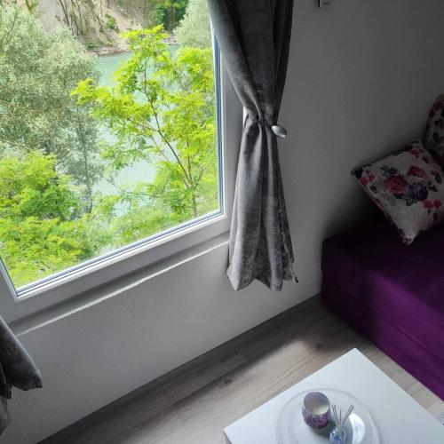 a room with a window and a table with a plate at City River View in Foča