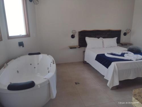 a bedroom with a bed and a bath tub at Chalés Vale Sereno in Camanducaia