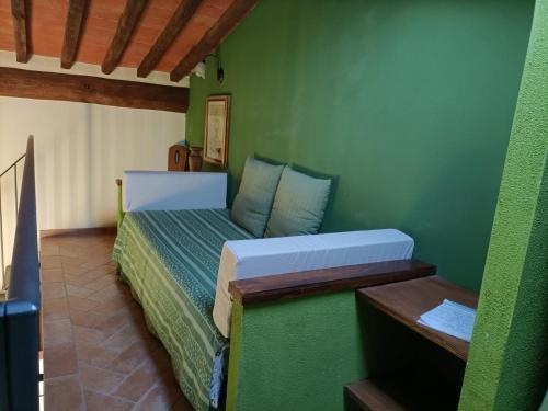 Un dormitorio con una pared verde y una cama. en Agriturismo Scannano en Serre di Rapolano