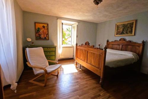 a bedroom with a bed and a chair and a window at La Mulattiera - vista lago in Baveno