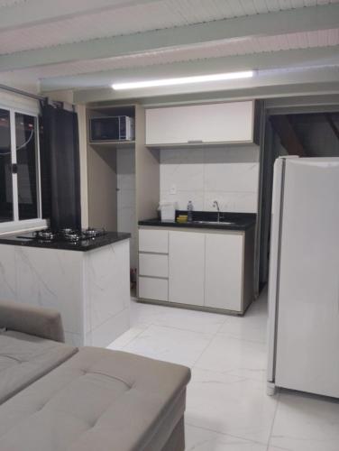 a kitchen with white cabinets and a refrigerator at Cananéia Chalé 23 in Ilha Comprida