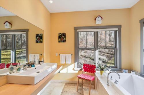 a bathroom with two sinks and a tub and two windows at Cody's Clubhouse in Waterbury Center