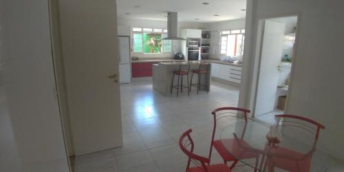 uma cozinha com uma mesa de vidro e cadeiras vermelhas em CASA CLUBE EM PENEDO RJ em Itatiaia