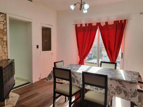 uma sala de jantar com uma mesa com cadeiras e cortinas vermelhas em Los manzanares, casa histórica em Veintiocho de Noviembre