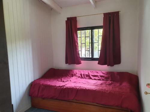 a bedroom with a red bed and a window at Los manzanares, casa histórica in Veintiocho de Noviembre