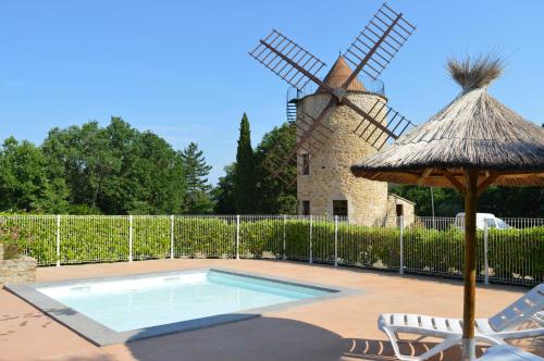 een zwembad met een windmolen op de achtergrond bij le moulin in Vallon-Pont-dʼArc