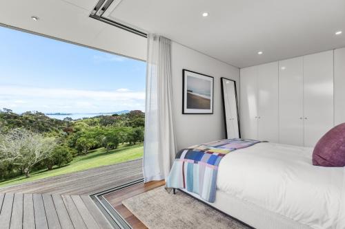 a bedroom with a bed and a large window at Number 29 in Oneroa