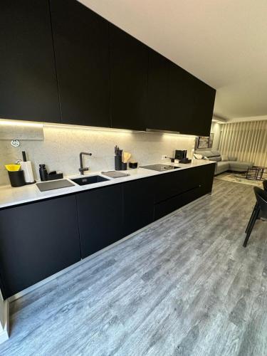 a kitchen with black cabinets and a wooden floor at Alojamento Gândara in Praia de Mira