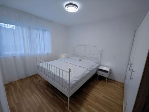 a bedroom with a white bed and a night stand at A côté de l'îles Sion in Sion