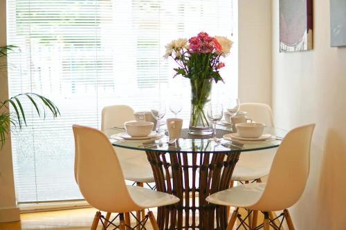 a dining room table with a vase of flowers on it at Superior Canary Wharf O2 Arena 2Bed Apartment in London