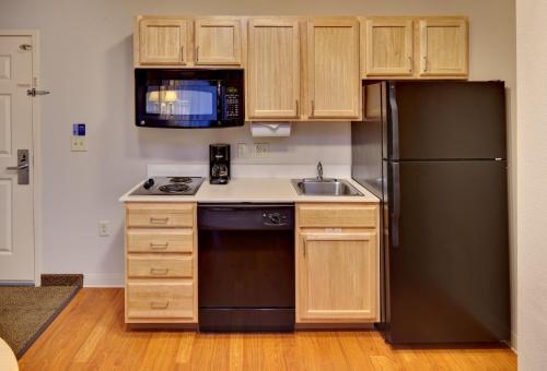 uma cozinha com um frigorífico preto e um lavatório em Candlewood Suites - Peoria at Grand Prairie, an IHG Hotel em Peoria