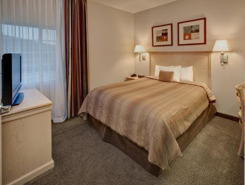 a hotel room with a bed and a flat screen tv at Candlewood Suites - Peoria at Grand Prairie, an IHG Hotel in Peoria
