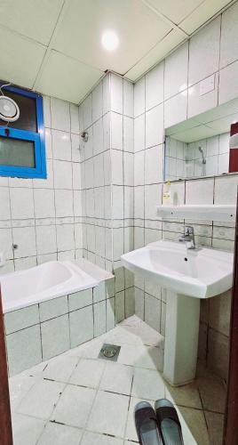 a bathroom with a sink and a tub and a mirror at Anju's sweet Stay in Sharjah