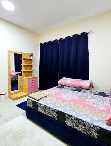 a bedroom with a bed and a blue curtain at Anju's sweet Stay in Sharjah