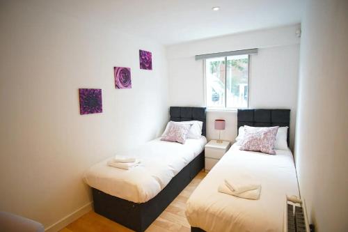 two twin beds in a room with a window at Superior Canary Wharf O2 Arena 2Bed Apartment in London