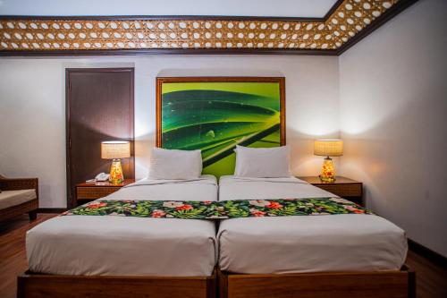 two beds in a room with two lamps and a painting at Club Agutaya in San Vicente