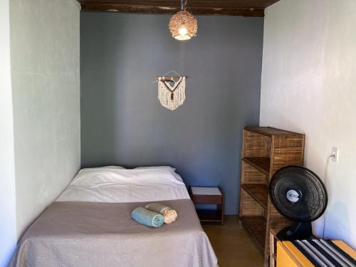 a small bedroom with a bed and a fan at Caju com Mel in Moreré