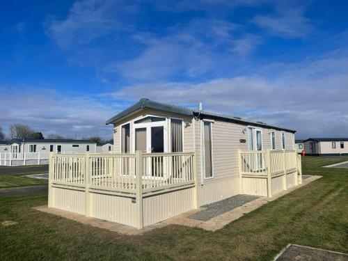 a small house with a white fence in a yard at Golden Anchor - The Chamonix - Coastal Caravan Breaks in Chapel Saint Leonards