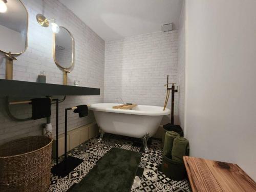 een witte badkamer met een bad en een spiegel bij L'Elégant in Montauban