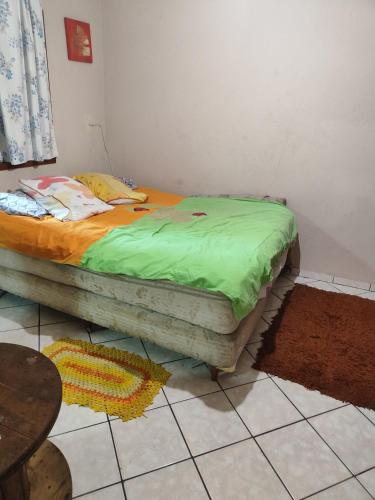 a bed in a room with a green blanket on it at Suíte independente a 10 minutos da praia in Vila Velha