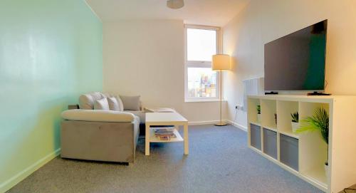 uma sala de estar com um sofá, uma mesa e uma televisão em Entire Flat in Canary Wharf em Londres
