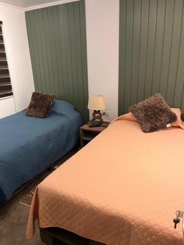 1 dormitorio con 2 camas y mesa con lámpara en Hostal Lodge Wine Colchagua, en Nancagua