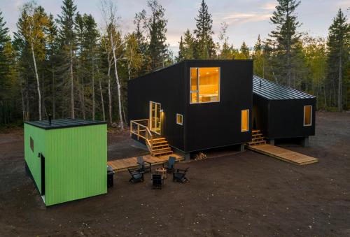 a black tiny house in the woods with a green door at Ski Hill Cabins and Saunas in Lutsen