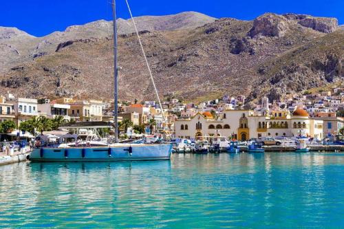 a sail boat docked in a harbor with a town at Pelagos Seafront Accommodation - George in Myrties