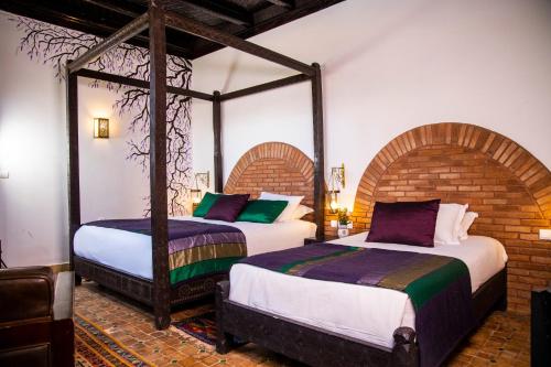 two beds in a room with two bedsitures at Palais Riad Hida in Oulad Barrehil