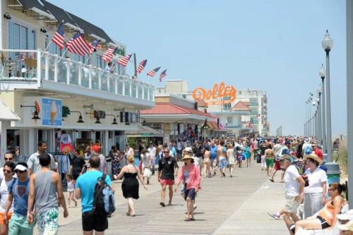 a large crowd of people walking down a boardwalk at Modern Beachside Bliss: 2 Bed/2 Bath Condo Haven in Rehoboth Beach