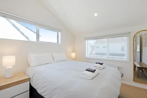 um quarto com uma cama branca e toalhas em Lyall Bay Parade Apartment em Wellington