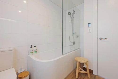 y baño con ducha, aseo y taburete. en Lyall Bay Parade Apartment, en Wellington