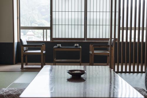 a room with a table and chairs and a bowl on it at Takamiya Bettei Kuon in Tsuruoka