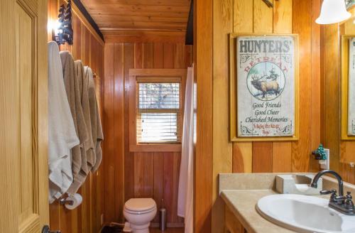 ein Bad mit einem Waschbecken, einem WC und einem Poster in der Unterkunft Deer Island in Bigfork