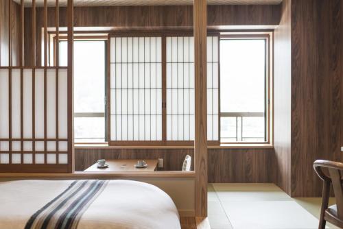 a bedroom with wooden walls and windows and a bed at Takamiya Bettei Kuon in Tsuruoka