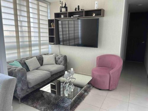 uma sala de estar com um sofá e uma cadeira rosa em Apartamento nuevo en Airbnb en miramar, excelente em Barranquilla
