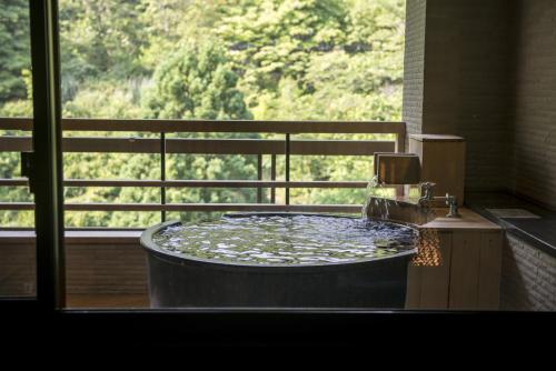 a large bath tub in a room with a window at Takamiya Bettei Kuon in Tsuruoka