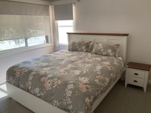 a bedroom with a large bed with a floral bedspread at Herbert Cottage in Tumut
