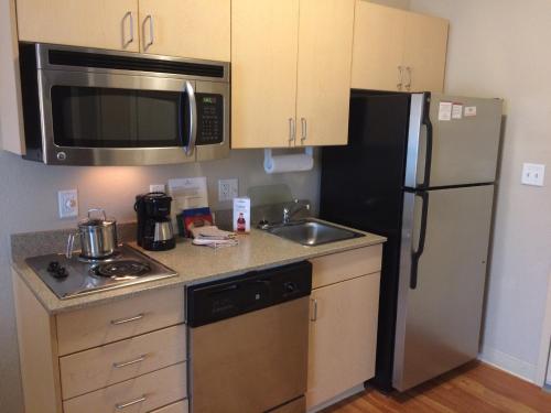 a small kitchen with a refrigerator and a sink at Candlewood Suites Watertown Fort Drum by IHG in Evans Mills