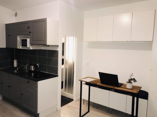 une cuisine avec des placards blancs et un ordinateur portable sur une table dans l'établissement Studio 17 - Cosy & Modern, à Paris