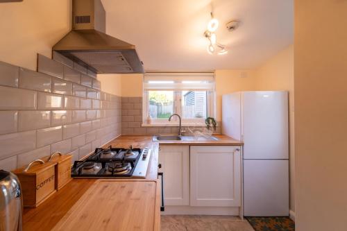 een keuken met een fornuis en een witte koelkast bij Bumble Bee Cottage Witney Serviced accommodation in Witney