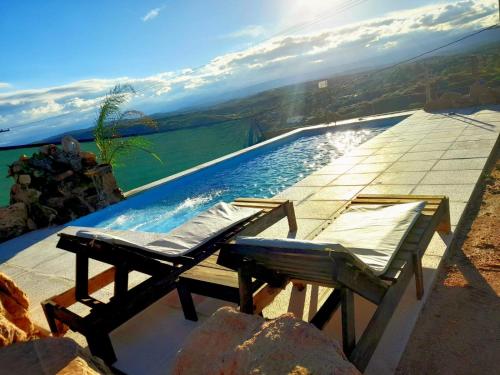 a pool with two chairs and a table next to it at Cabañas ALTOS DEL MOLLE en VCP in Villa Carlos Paz