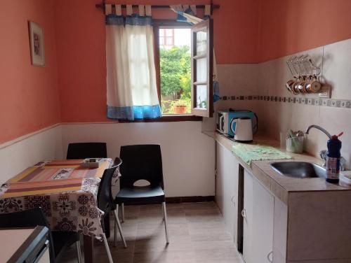 eine Küche mit einem Waschbecken, einem Tisch und einem Fenster in der Unterkunft Casa del Arte in Salta