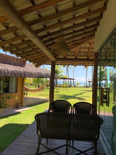 a patio with two chairs under a wooden pergola at Sítio Maravilha Parracho e Sonja (Casa Pé Na Areia) in Arraial d'Ajuda