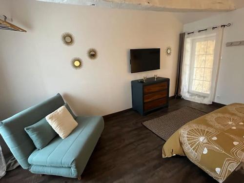 1 dormitorio con sofá, TV y cama en Charmante maison, vue imprenable en Nanclars