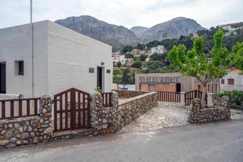 a building with a gate and a stone wall at Pelagos Seafront Accommodation - George in Myrties