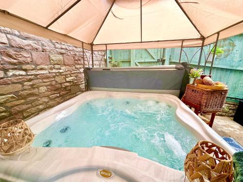 a large jacuzzi tub in a patio with an umbrella at *Brecon Beacons,Log Burner, hot tub Dogs Welcome* in Crickhowell