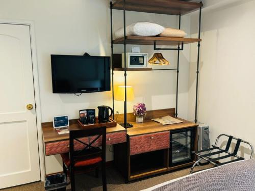 een kamer met een bureau met een televisie en een bureau met een stoel bij LP Los Portales Hotel Cusco in Cuzco