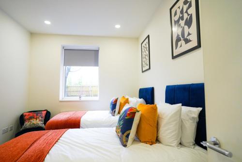 a bedroom with two beds with colorful pillows at Classy Modern Flat: Free Parking, Gym & Roof Garden in Stevenage